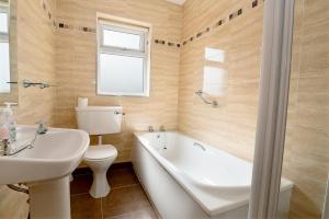 a bathroom with a tub and a toilet and a sink at Bradleys Cottage Creeslough in Creeslough