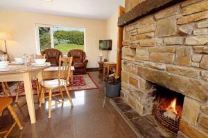 a living room with a stone fireplace and a table and chairs at Bradleys Cottage Creeslough in Creeslough