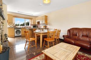a living room with a table and a leather couch at Bradleys Cottage Creeslough in Creeslough