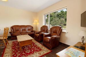 a living room with leather furniture and a window at Bradleys Cottage Creeslough in Creeslough