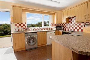 a kitchen with a washing machine and a window at Bradleys Cottage Creeslough in Creeslough