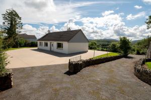 a white house with a black roof on a driveway at Bradleys Cottage Creeslough in Creeslough