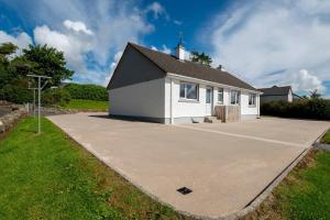a white and black house with a parking lot at Bradleys Cottage Creeslough in Creeslough
