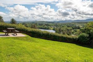 a picnic table in a field with a view of a river at Bradleys Cottage Creeslough in Creeslough