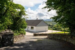 a white house with a black roof and a driveway at Bradleys Cottage Creeslough in Creeslough