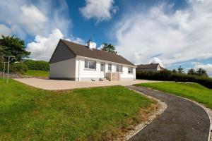 a white house with a black roof and a driveway at Bradleys Cottage Creeslough in Creeslough
