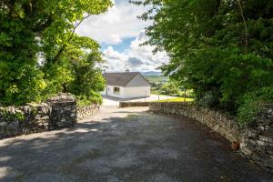 a road leading to a white house with a stone wall at Bradleys Cottage Creeslough in Creeslough
