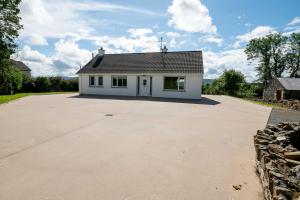 a white house with a roof on a driveway at Bradleys Cottage Creeslough in Creeslough