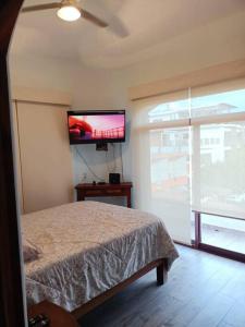 a bedroom with a bed and a tv on the wall at “Casa Juanita” in Lo de Marcos