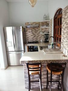 a kitchen with a refrigerator and a counter with two chairs at “Casa Juanita” in Lo de Marcos