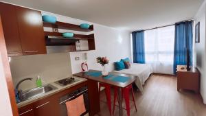 a small kitchen with a sink and a table with a stove at Apartamentos Bulnes in Santiago