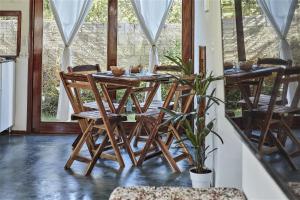 einen Holztisch und Stühle in einem Zimmer mit Fenstern in der Unterkunft Condomínio Villa Conduru - Casa completa in Prea