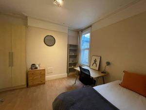 Schlafzimmer mit einem Bett, einem Schreibtisch und einem Fenster in der Unterkunft Ealing Hububb Stay in Ealing