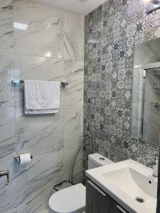 een badkamer met een wit toilet en een wastafel bij Moderno Apartamento en Avenida Balboa in Panama-Stad
