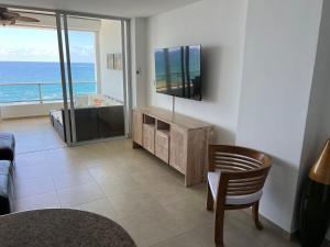 a living room with a tv and a table and a chair at Marbella Towers - Ocean Front in Juan Pedro