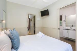 een wit bed met blauwe kussens in een kamer bij Reflections Corindi Beach - Holiday Park in Corindi