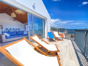 een terras met stoelen en een bank op een balkon bij Casa da Baleia T2 in Vila Franca do Campo
