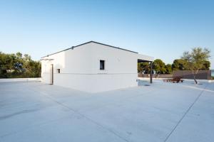 a white building with a bench in a park at Beach Haven house with pool and Jacuzzi in Kaštela