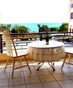 a table with a bottle of wine and two chairs at Sunny home crete in Ierápetra