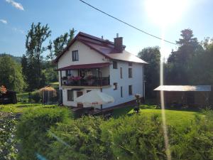 a white house with a balcony and an umbrella at Apartament Berezka 667-108-706 in Polańczyk