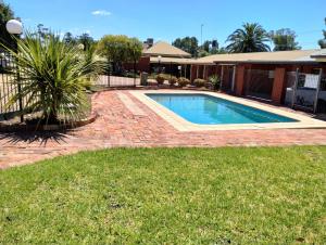 a swimming pool in a yard next to a house at Junction Motel Wagga in Wagga Wagga