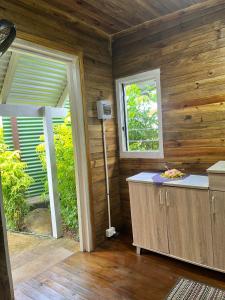 Habitación con paredes de madera y cocina con ventana. en Camp Taveuni, en Matei