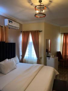 a bedroom with a large white bed with a window at Bamod Hotel and Suites in Lekki
