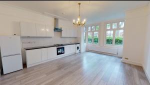 a large kitchen with white cabinets and a chandelier at Homely 3 Bedroom Ground Floor Flat in London