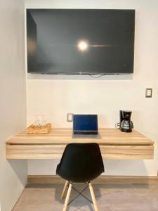 a desk with a laptop and a television on a wall at Darwin 8 in Mexico City