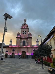 a large building with a clock tower with pink lights at Hermoso apartamento en Pasto. Central parque San Andrés in Pasto +8 photos