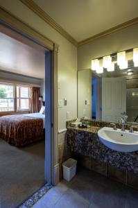 een badkamer met een wastafel, een bed en een spiegel bij Kaslo Hotel in Kaslo