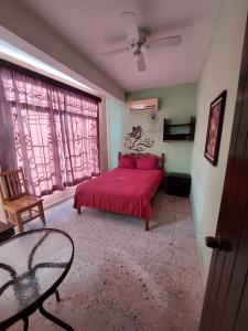 sypialnia z czerwonym łóżkiem i szklanym stołem w obiekcie San Diego Tu Casa w mieście Campeche