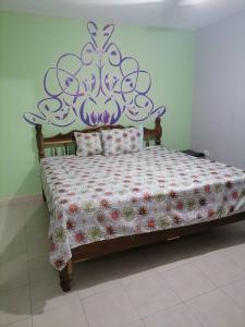 a bedroom with a bed with a floral bedspread at San Diego Tu Casa in Campeche