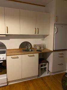 a kitchen with white cabinets and a sink at Cosy house near airport in Sørvágur