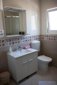 Un baño con lavabo, inodoro y espejo. en White Pearl 4, en Sevid