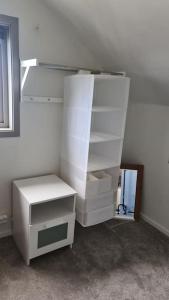 a white closet with shelves and a window at Cosey 1 bedroom loft with free parking in Stavanger
