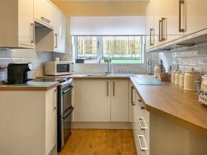 a kitchen with white cabinets and a wooden counter top at Harris House in Staveley
