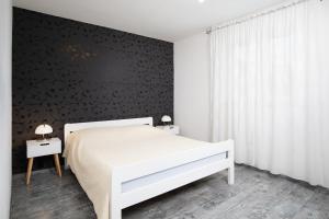 een slaapkamer met een wit bed en een zwarte muur bij Apartments with a parking space Valbandon, Fazana - 7227 in Fažana