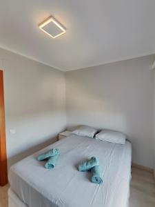 Una cama blanca con dos almohadas azules. en Family apartment Besos en Barcelona