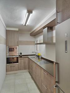 una cocina con electrodomésticos de acero inoxidable y armarios de madera en Family apartment Besos en Barcelona