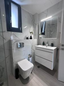 a white bathroom with a toilet and a sink at ἕαR Exceptional Residence in Nea Peramos +8 photos