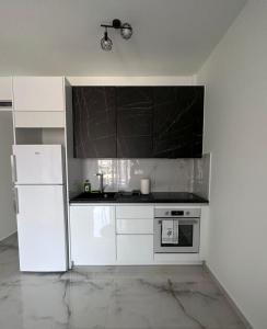 a kitchen with white cabinets and a white refrigerator at ἕαR Exceptional Residence in Nea Peramos
