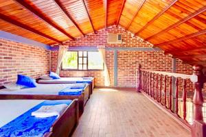 een kamer met 3 bedden en een bakstenen muur bij Finca Hacienda el Morichal in Villavicencio