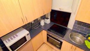 una pequeña cocina con microondas y fregadero en Home stay Rooms, en Slough