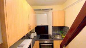 una pequeña cocina con armarios de madera y fregadero en Home stay Rooms, en Slough