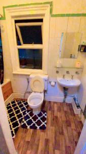 uma casa de banho com um WC, um lavatório e uma janela em Home stay Rooms em Slough