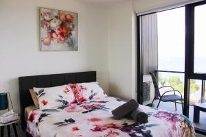 a bedroom with a bed with a floral comforter at Modern apartment with water view in Geelong in Geelong