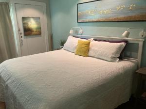 a bedroom with a bed with white sheets and yellow pillows at PAG Beachhouse Rentals in St. Pete Beach
