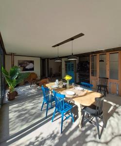 a dining room with a table and blue chairs at Wine Lodge de Viña Vultur en bosque nativo con piscina in Doñihue