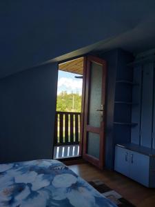 1 dormitorio con 1 cama y puerta a un balcón en Cabană cu teren de tenis, en Băniţa